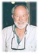 A man with a beard and glasses is wearing a white shirt.