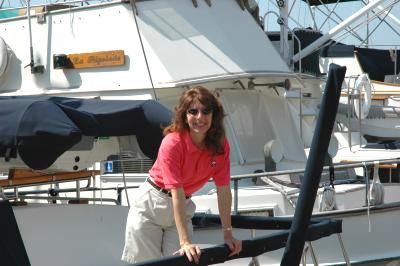 A woman in a pink shirt leans on a railing in front of a boat