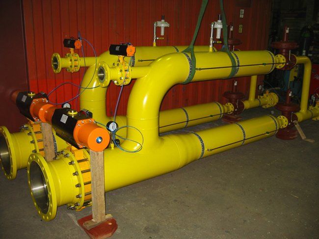 Yellow industrial pipes with black and orange valves.
