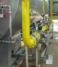 Ein paar gelbe Rohre sind mit einer Maschine in einer Fabrik verbunden.