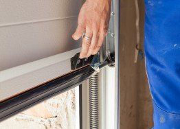 Worker open a garage door during repairing — Garage door spring repair in Harrisonville, MO