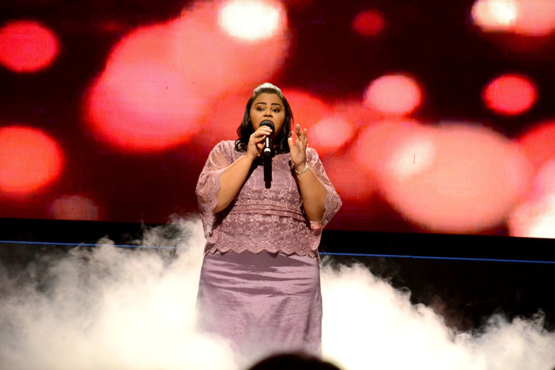 Uma mulher está cantando em um microfone no palco.
