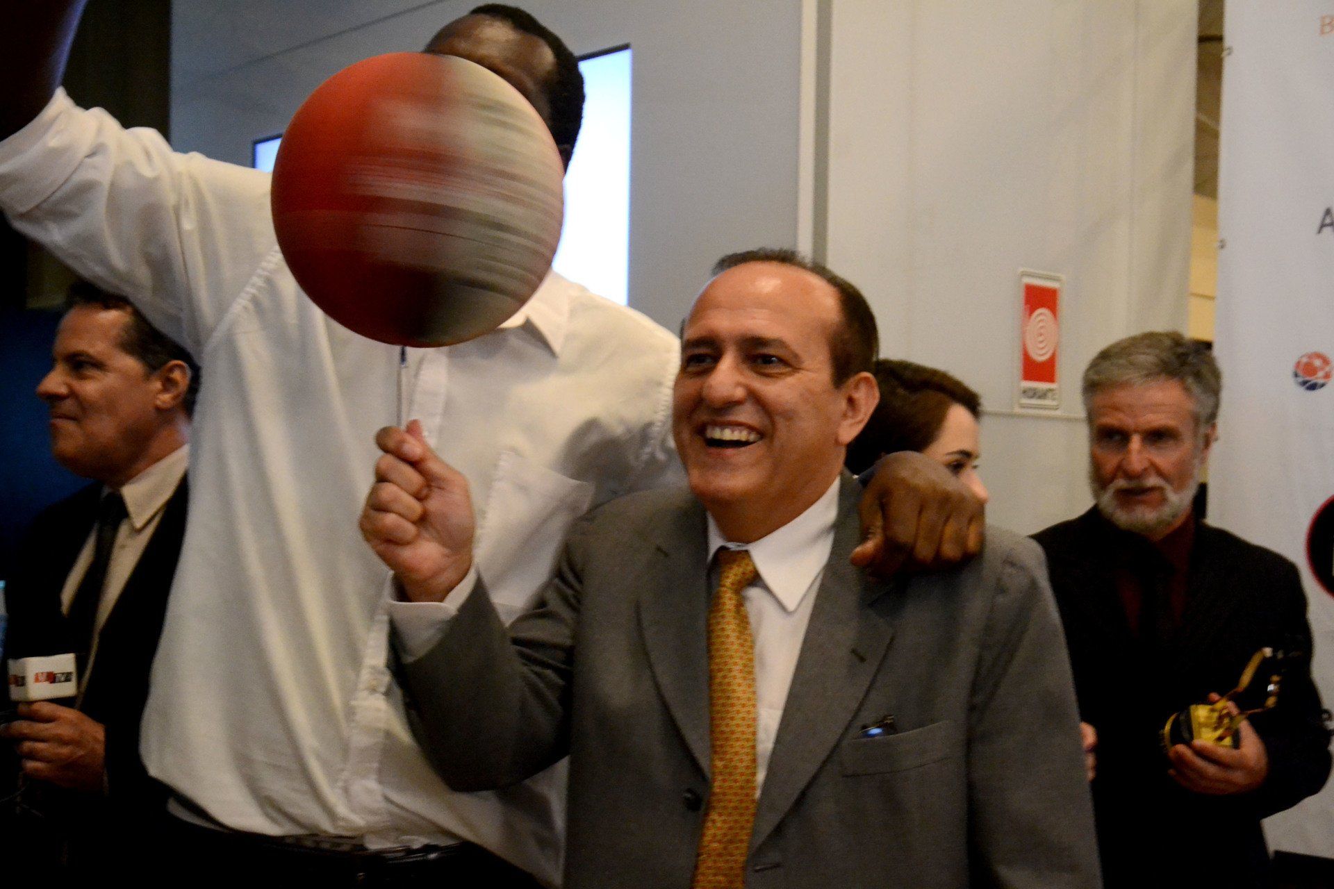Um homem de terno está segurando uma bola de basquete acima da cabeça