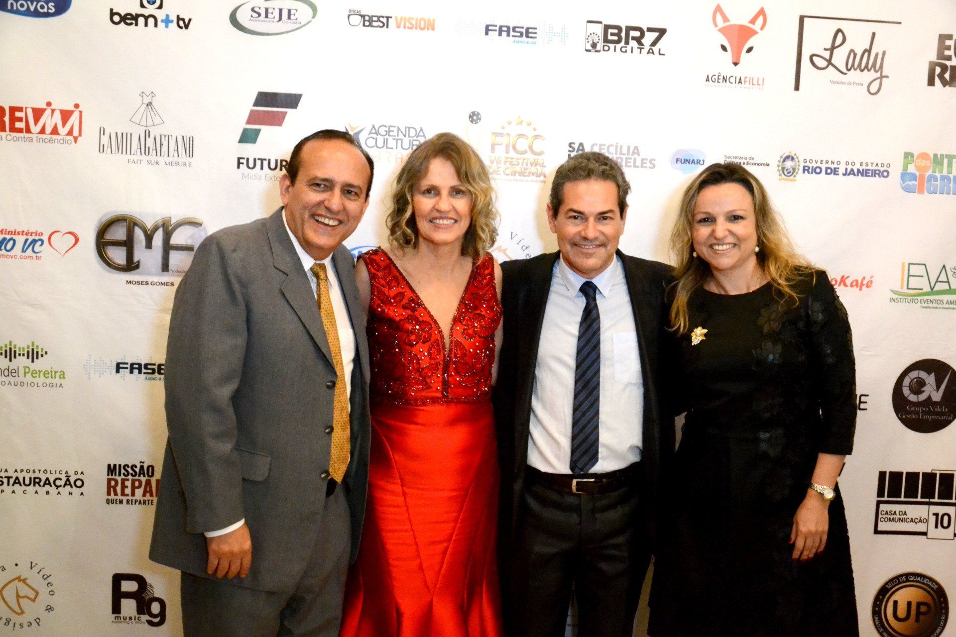 Um grupo de pessoas posando para uma foto em frente a uma parede com logotipos.