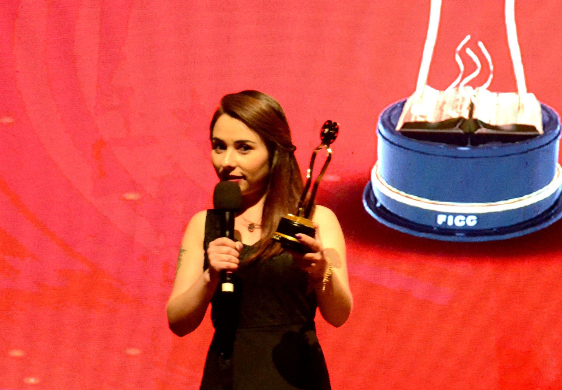 Uma mulher segurando um troféu ao lado de um bolo pico