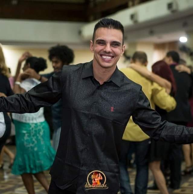 Um homem de camisa preta está sorrindo na frente de uma multidão