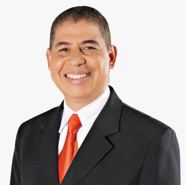 Um homem de terno e gravata sorri para a câmera