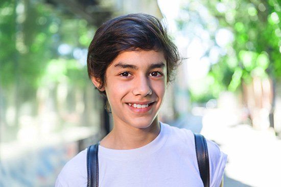 A young boy with a backpack is smiling for the camera.