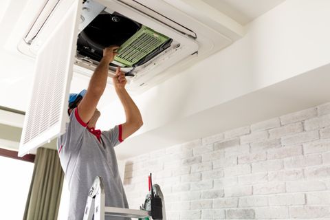 Air Conditioning Repair — Man Repairing the Air Conditioner in Anniston, AL Air Conditioning Repair — Man Repairing the Air Conditioner in Anniston, AL