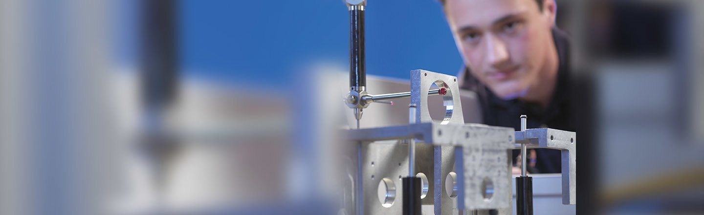 A man is looking at a machine in a factory.