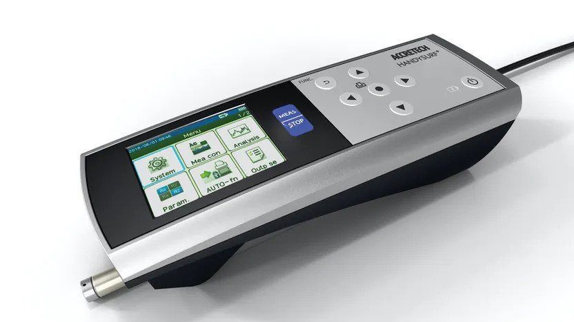 A remote control with a screen on it is sitting on a white surface.