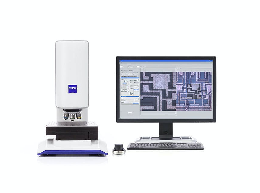 A computer monitor is sitting next to a microscope.