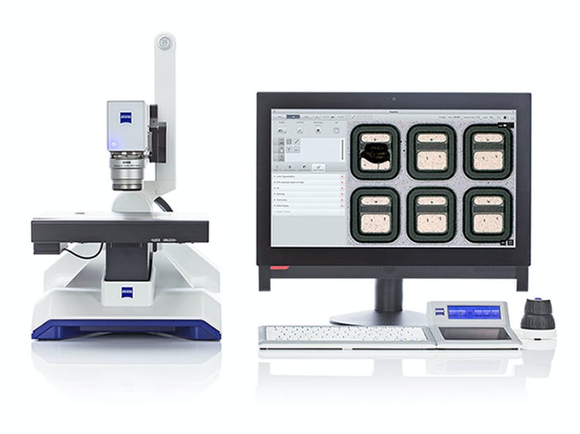 A microscope is sitting next to a computer monitor.