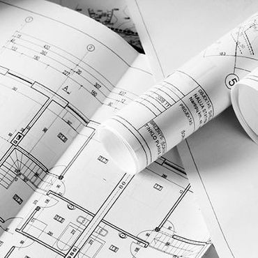 A bunch of rolls of blueprints are laying on top of each other on a table.