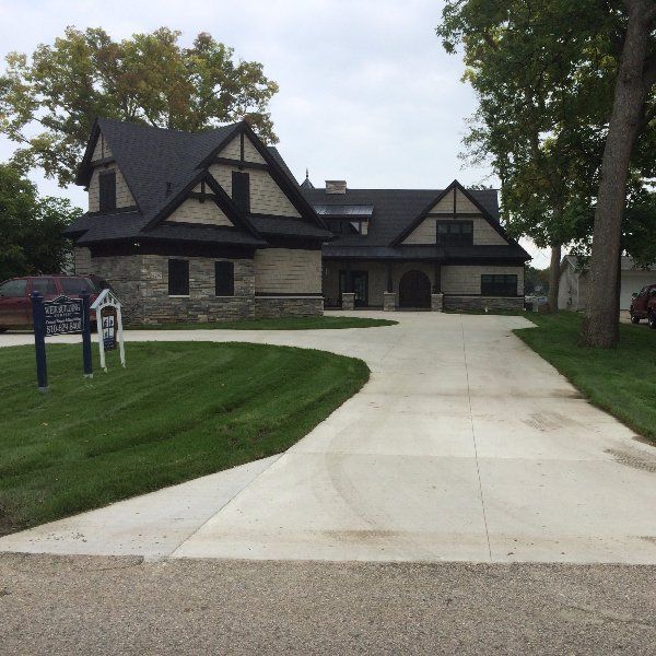 A large house with a concrete driveway leading to it