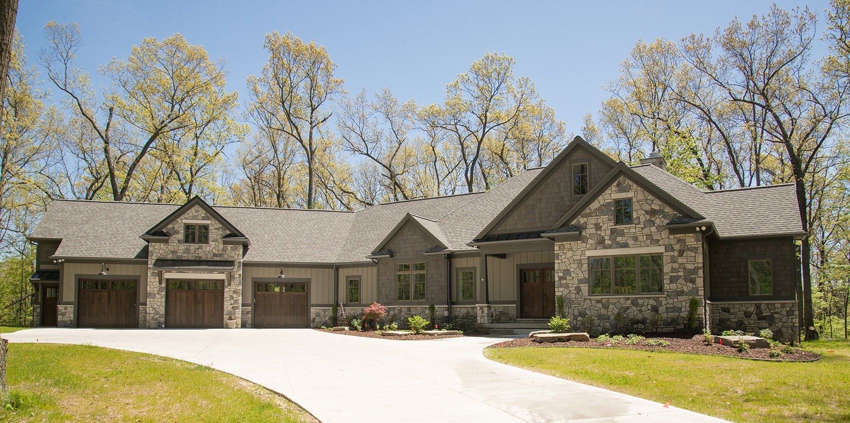A large house with a driveway leading to it is surrounded by trees.