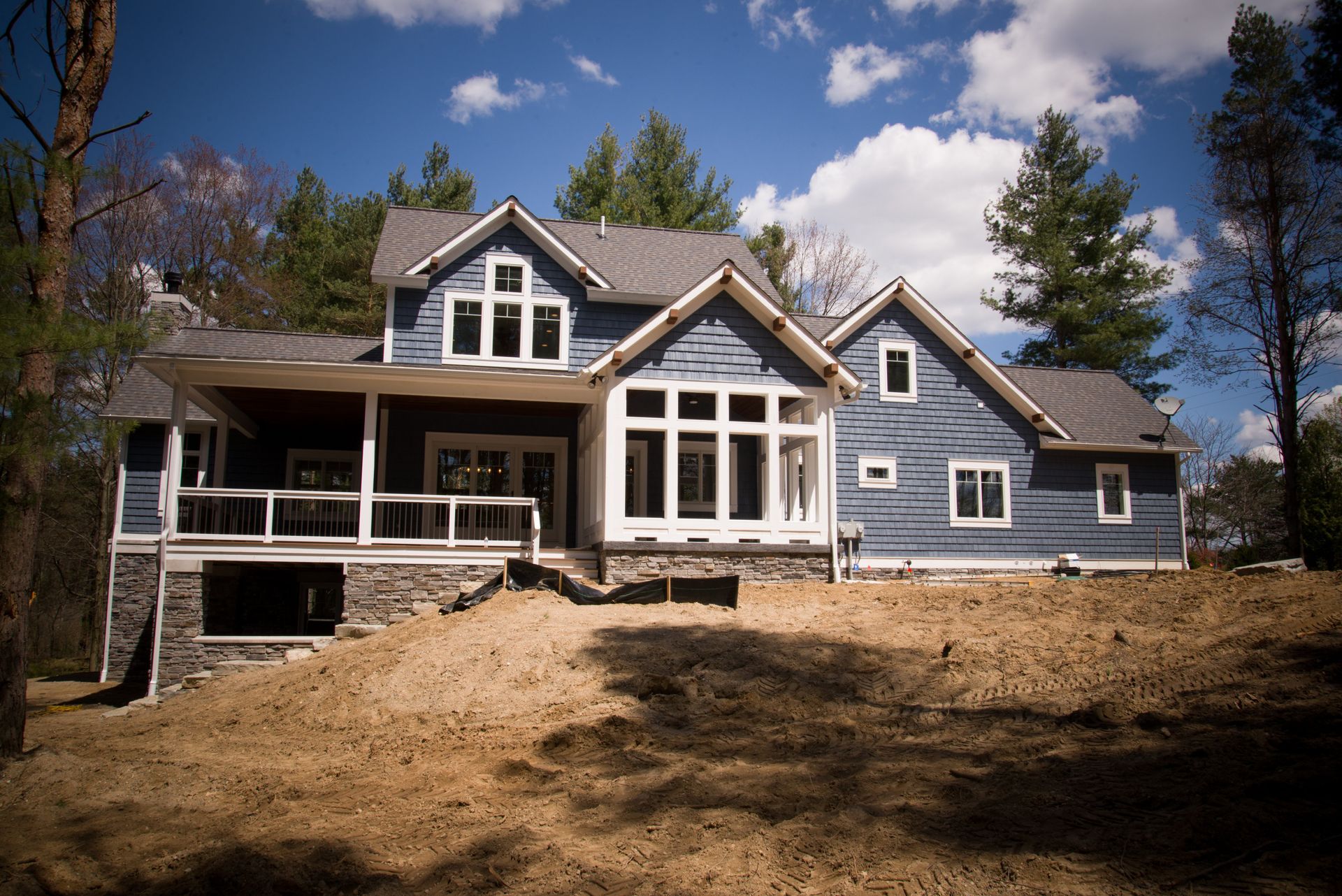 A large house with a lot of windows is sitting on top of a dirt hill