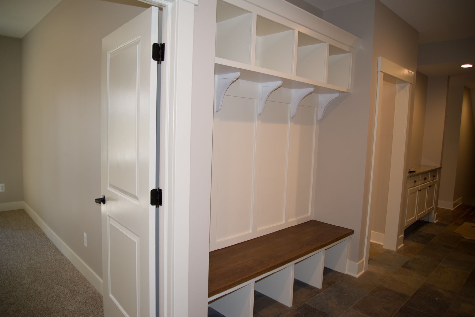 A hallway with a bench and a coat rack in a house.