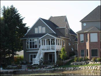 A large house with a balcony sits next to a brick house