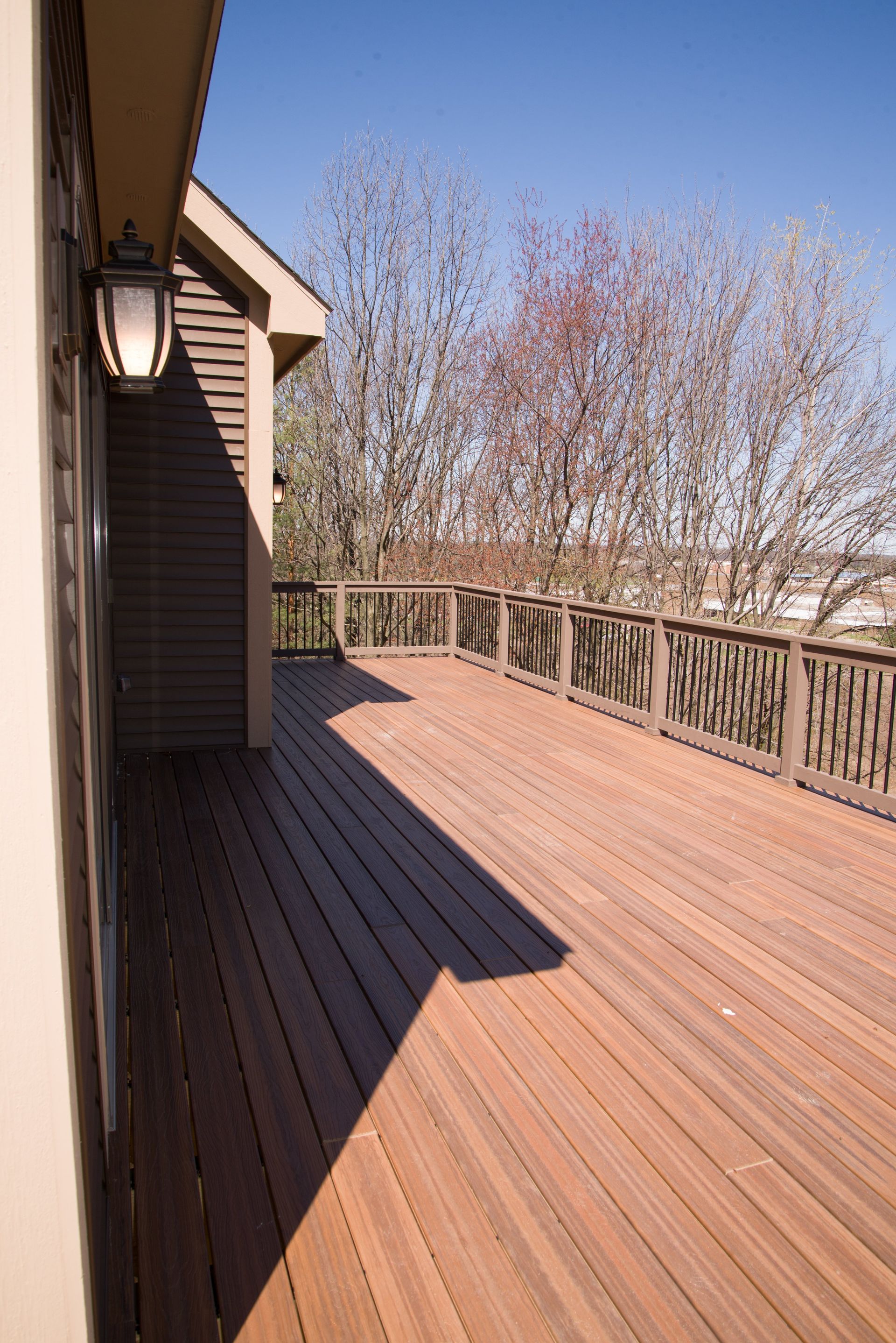 A large wooden deck with a fence and trees in the background