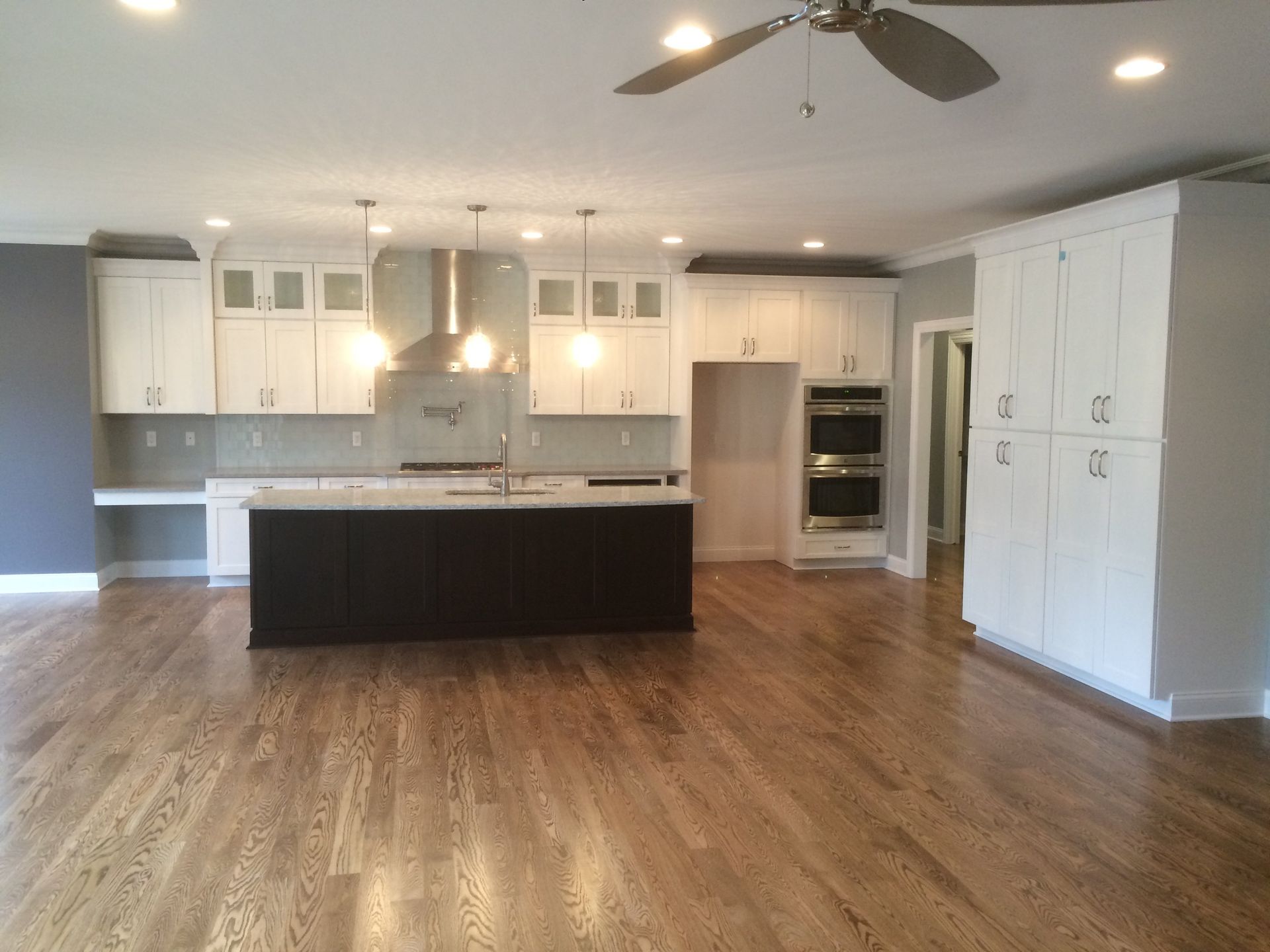 An empty kitchen with white cabinets and a ceiling fan