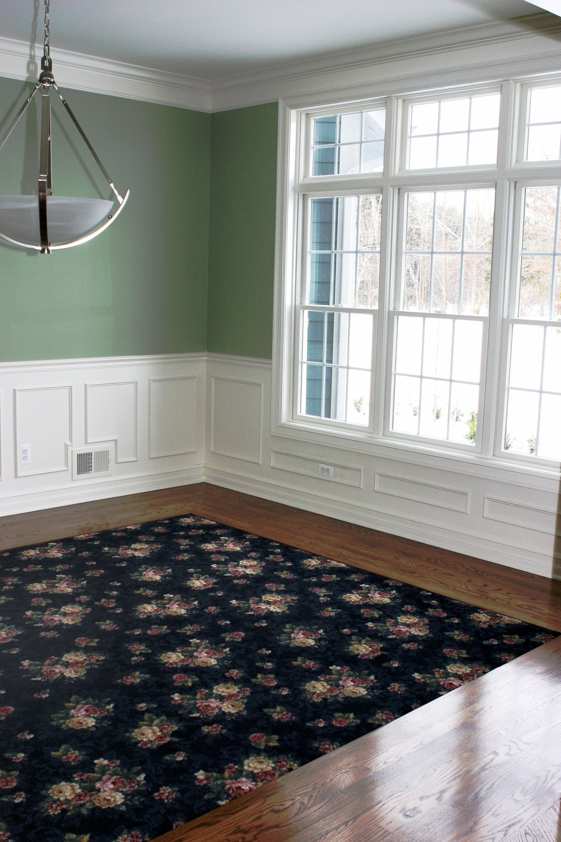 An empty room with green walls and a black rug