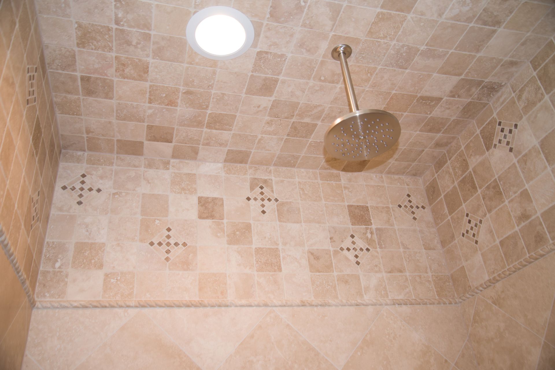 A shower head is hanging from the ceiling in a bathroom
