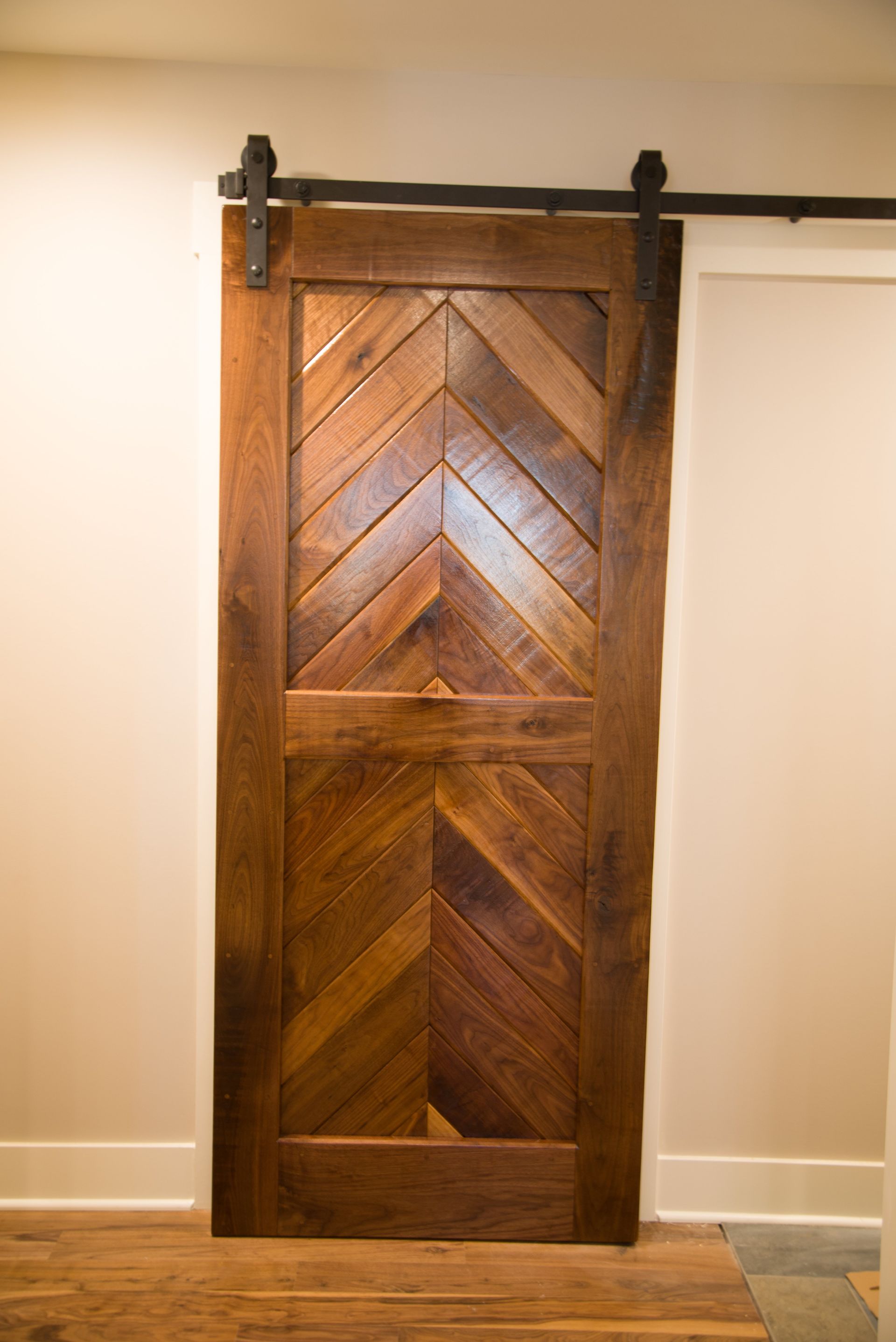 A wooden sliding barn door with a chevron pattern is hanging on a wall.