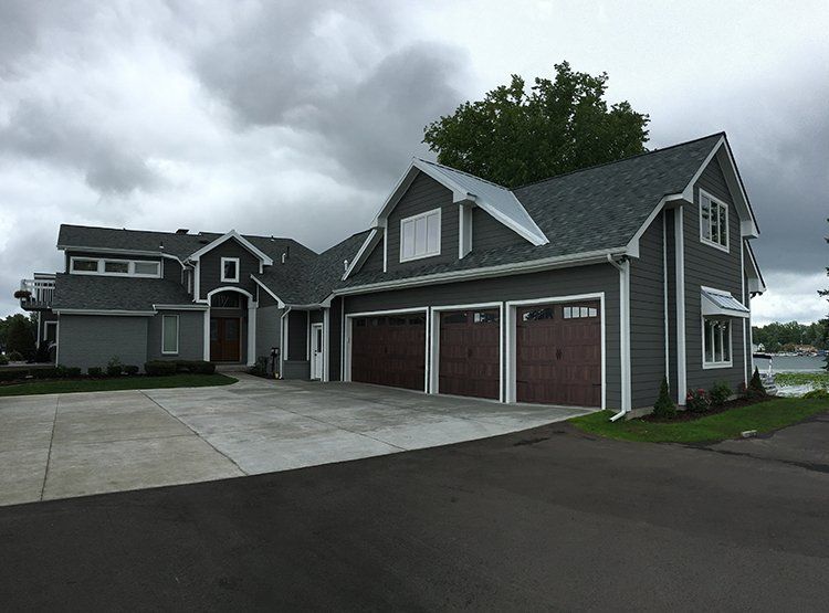 A large house with a lot of garage doors and a cloudy sky in the background.