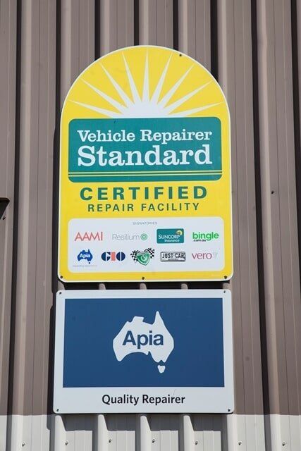 Vehicle Repair Facility Sign With Yellow Sunburst Logo and Blue Apia Quality Repair Plaque — A1 Panel & Paint In Emerald, QLD