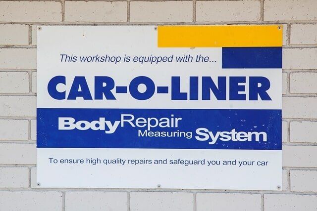 Car-O-Liner Body Repair Measurement System Sign on a White Brick Wall, Blue and White With Yellow Accent — A1 Panel & Paint In Emerald, QLD