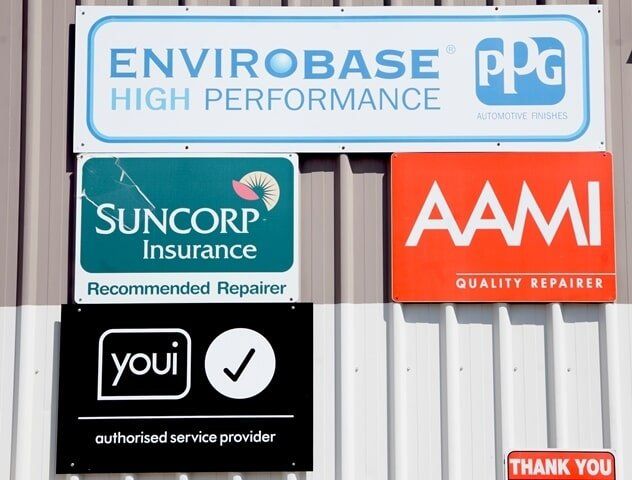 Car rEpair Shop Signs: Envirobase, Suncorp Insurance, Aami, and Youi Service Provider Logos on a Wall — A1 Panel & Paint In Emerald, QLD