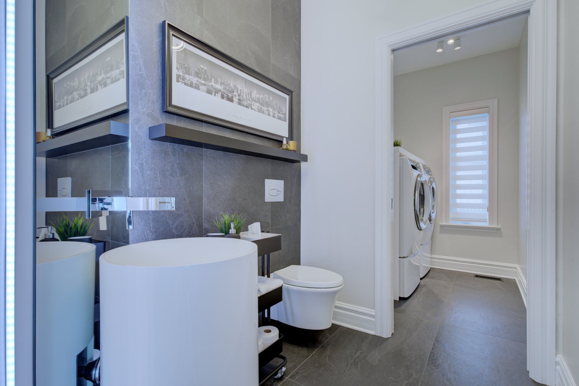 Une salle de bain avec lavabo , toilettes , miroir et laveuse et sécheuse.