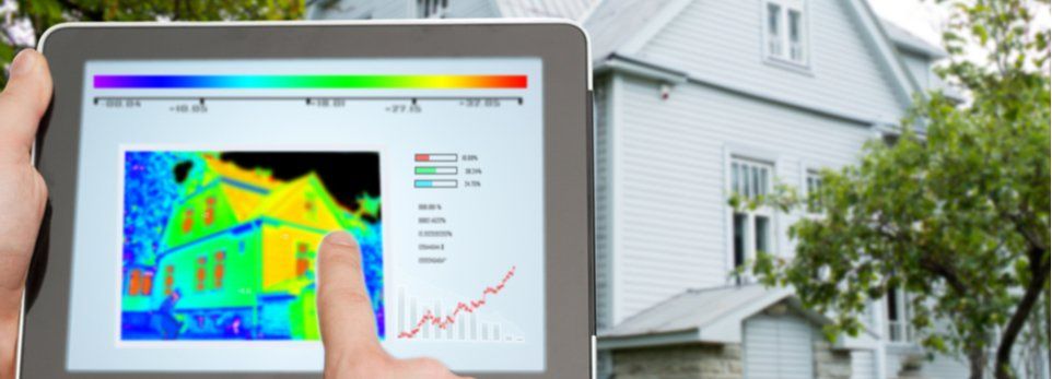Hände betrachten auf Tablet die Isolierung eines Hauses im Hintergrund