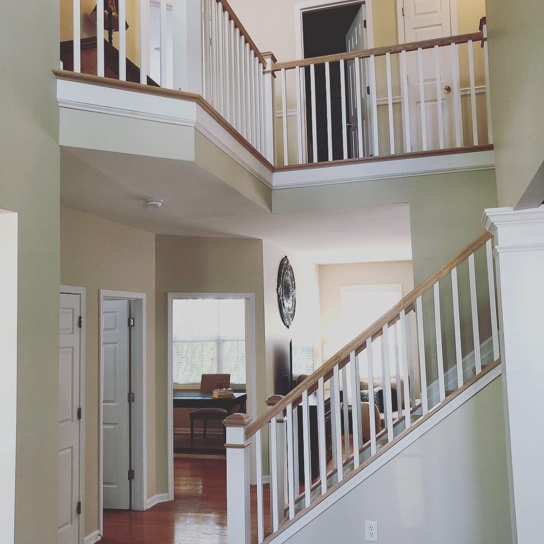 Interior balcony railing with white balusters and stained wood handrail overlooking a two-story foyer, Greenville SC