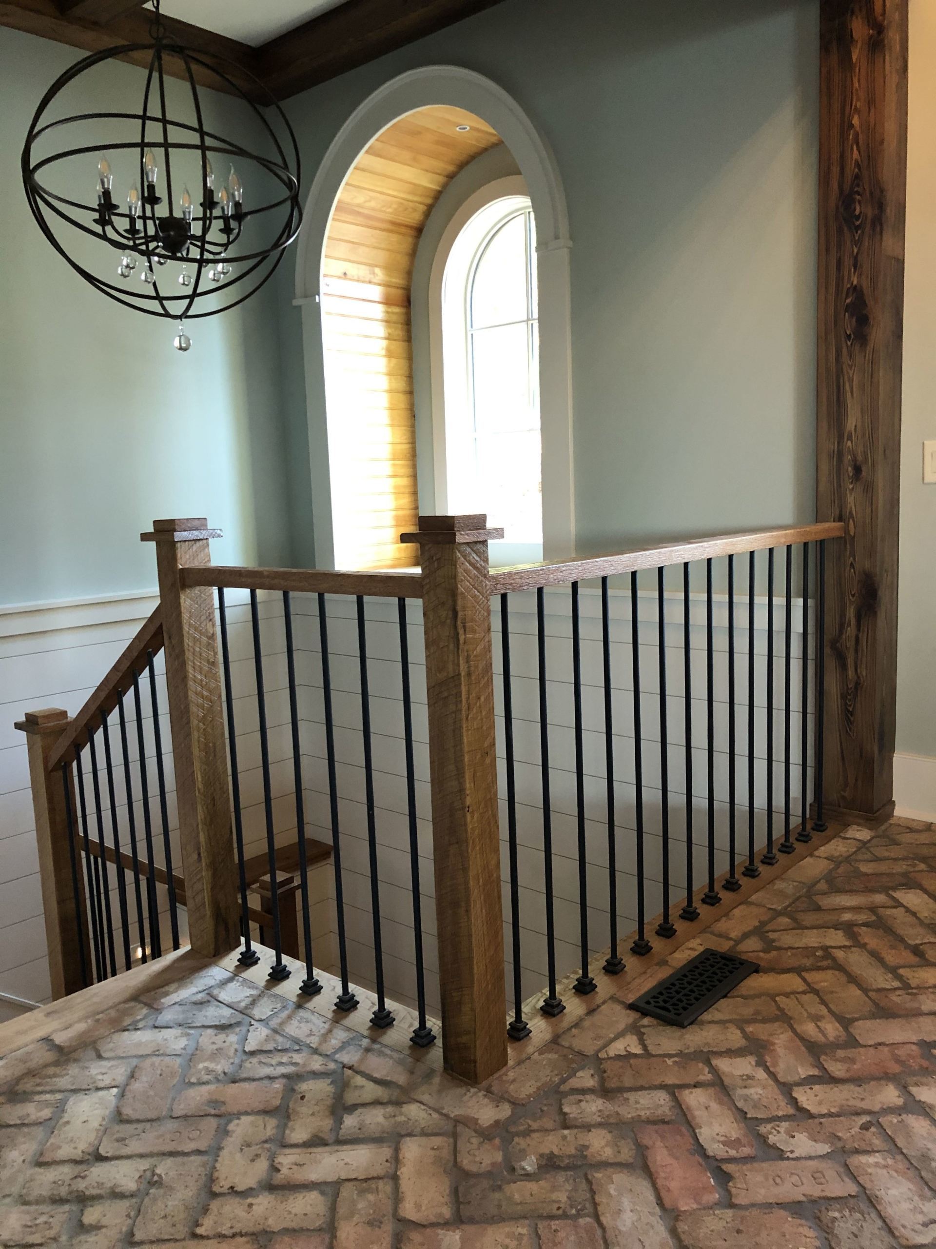 Two-story foyer with arched window, orb chandelier and iron balcony railing in Greenville, SC