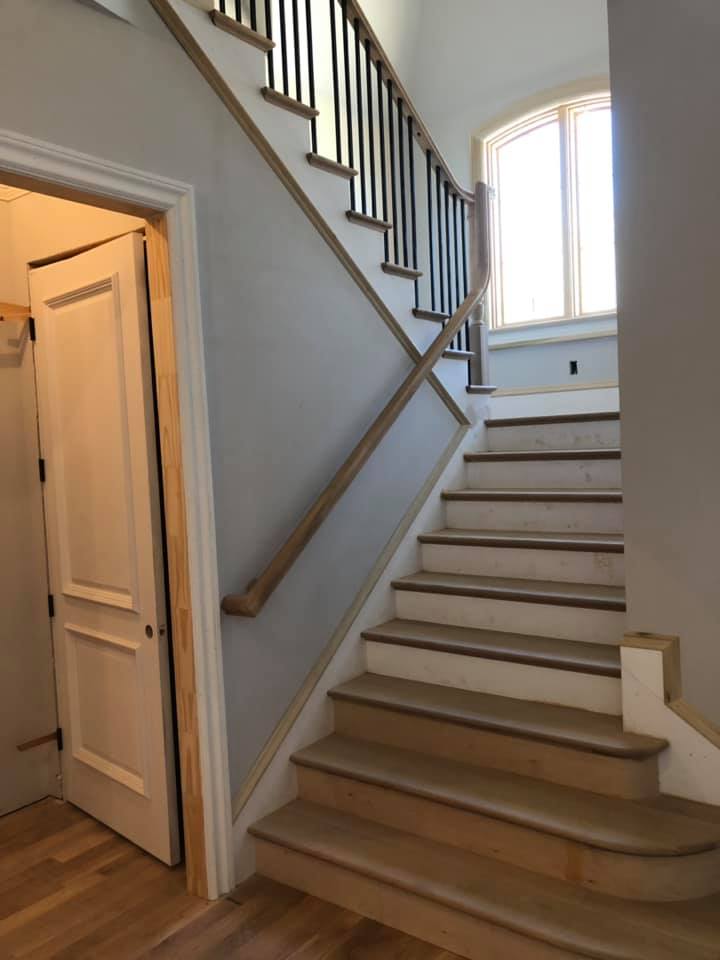 Custom staircase with black iron balusters and wood handrail near entryway, Greenville SC