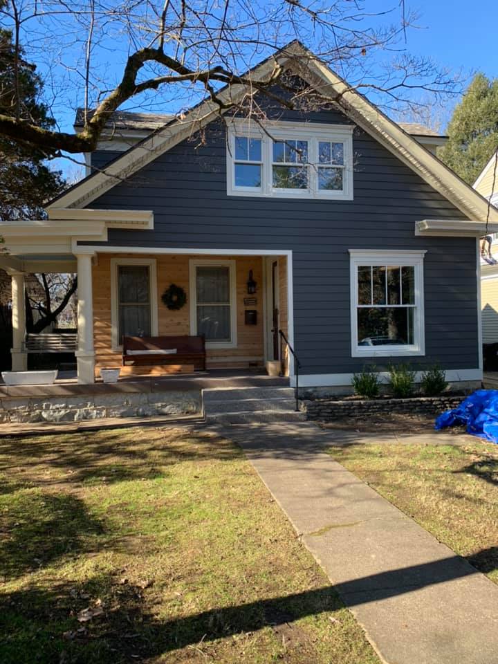 Gray house with white trim, front porch, and a walkway in a sunny yard