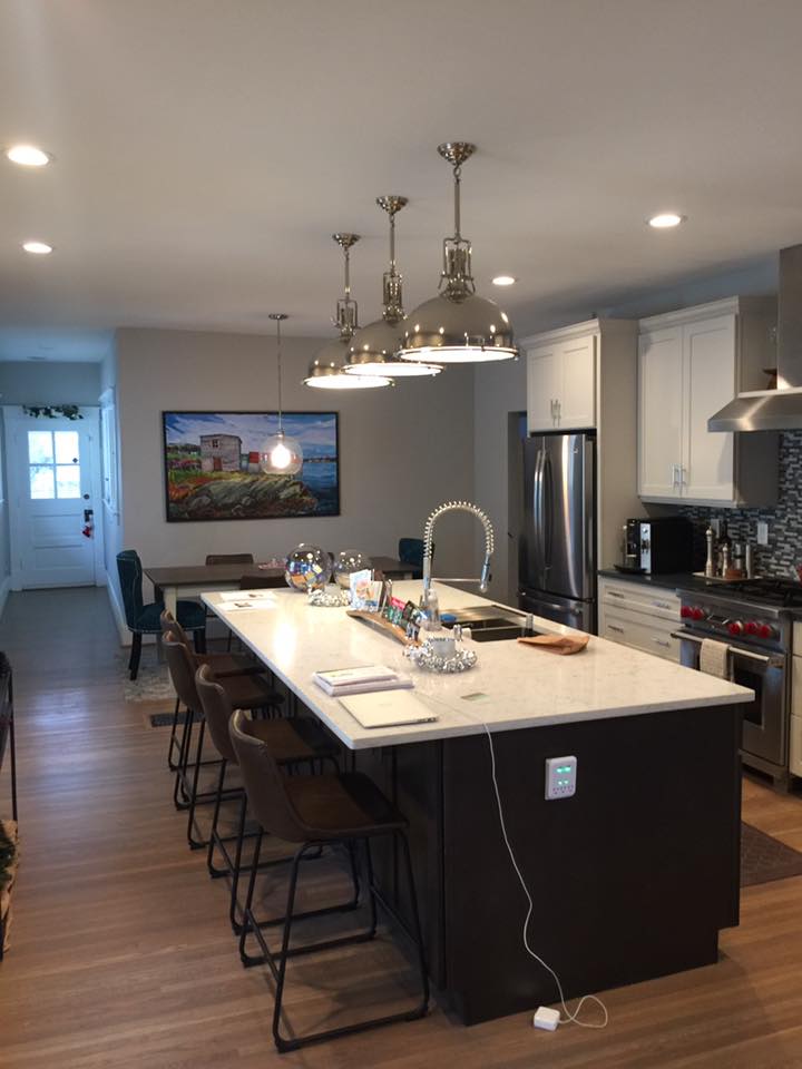 Modern kitchen with large island, pendant lights, stainless appliances, and bar stools