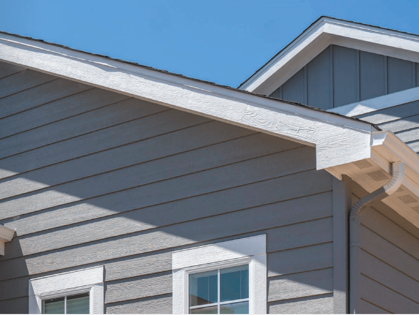 Gray house exterior with white trim and a gabled roof against a blue sky