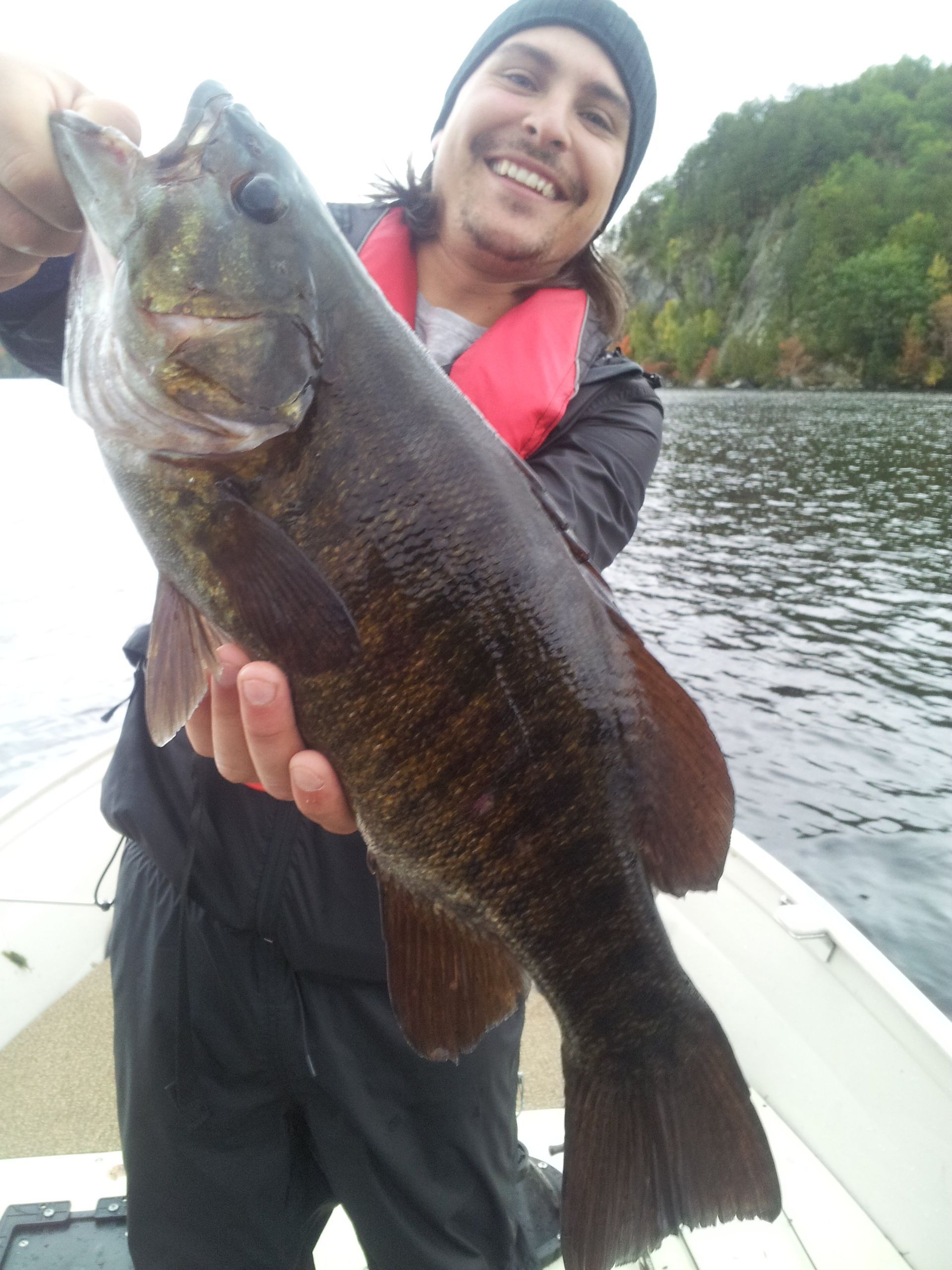 A man is holding a large fish on a boat