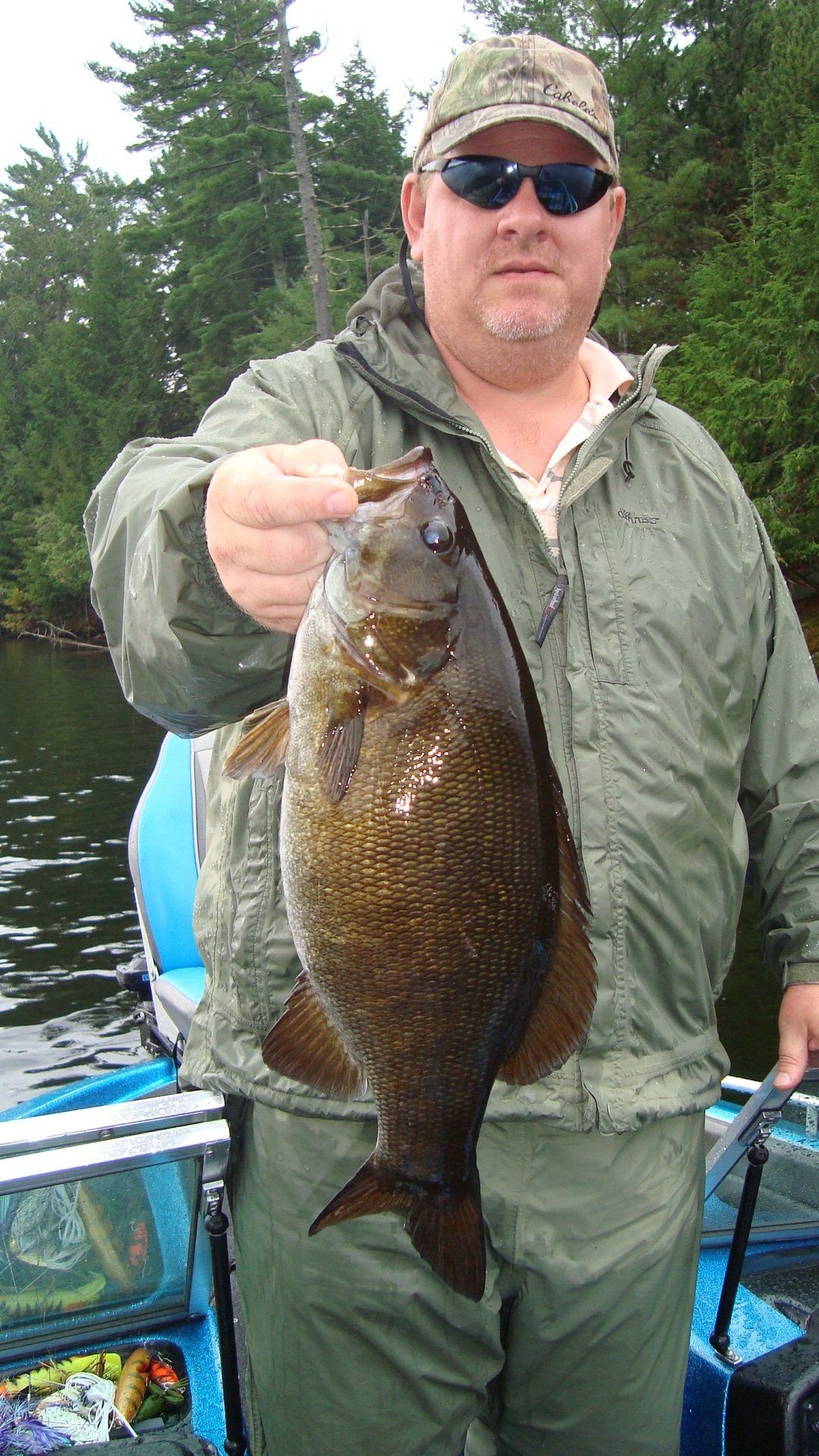 A man is holding a large fish in his hand while standing on a boat.