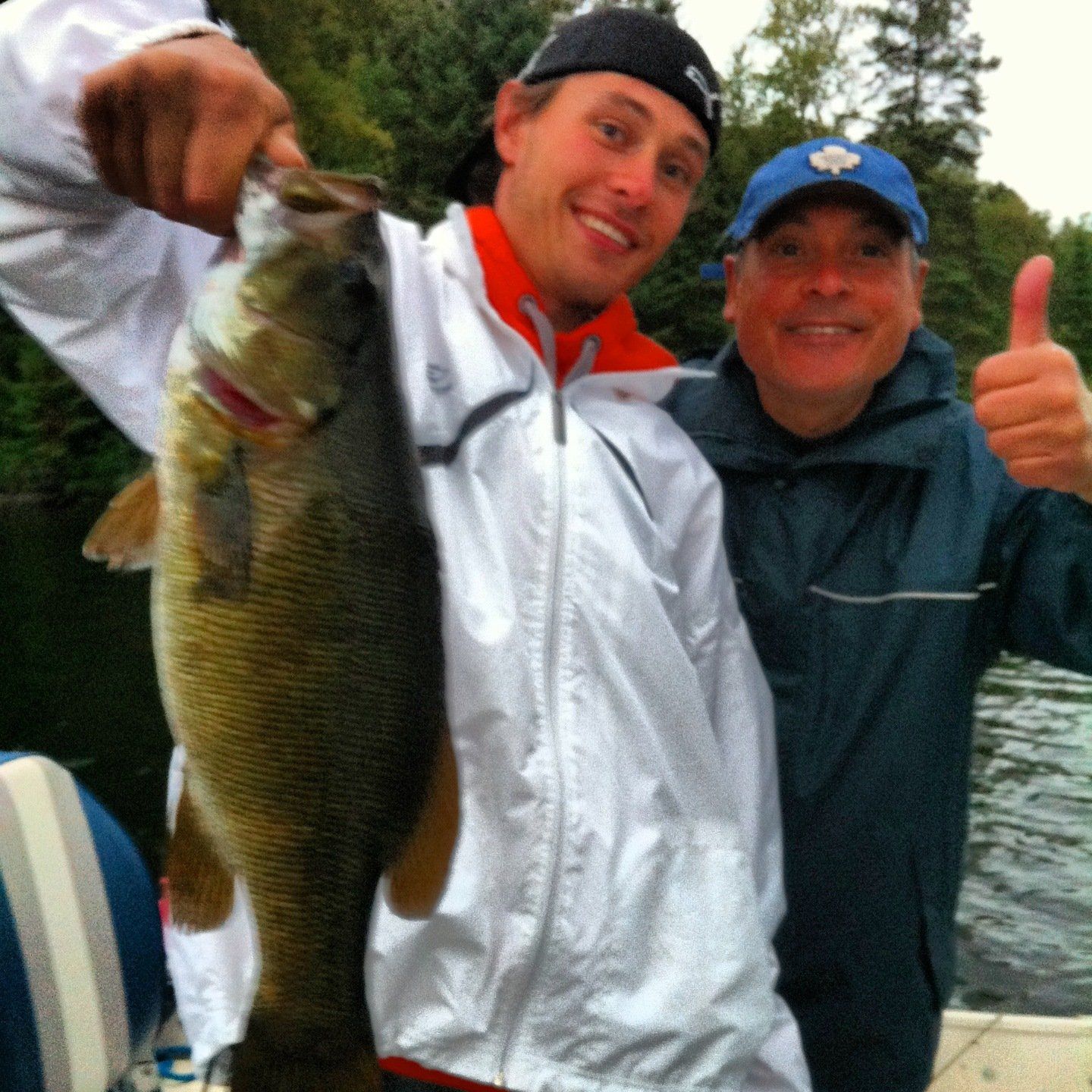 Two men holding a large fish and giving a thumbs up