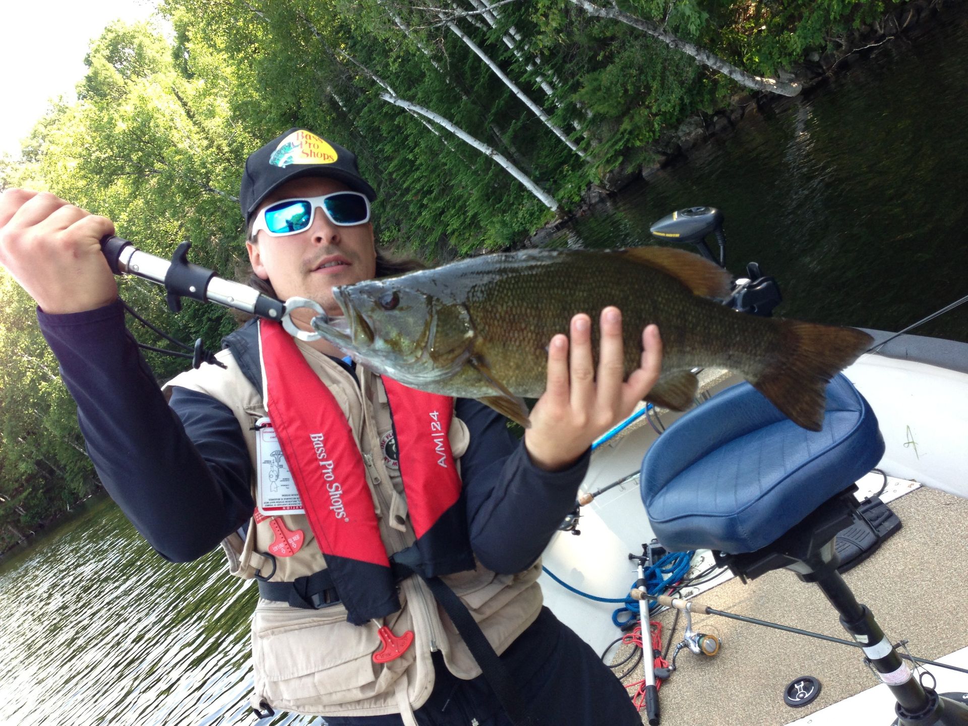A man wearing a life jacket is holding a large fish