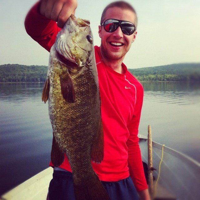 A man in a red shirt is holding a fish in his hand