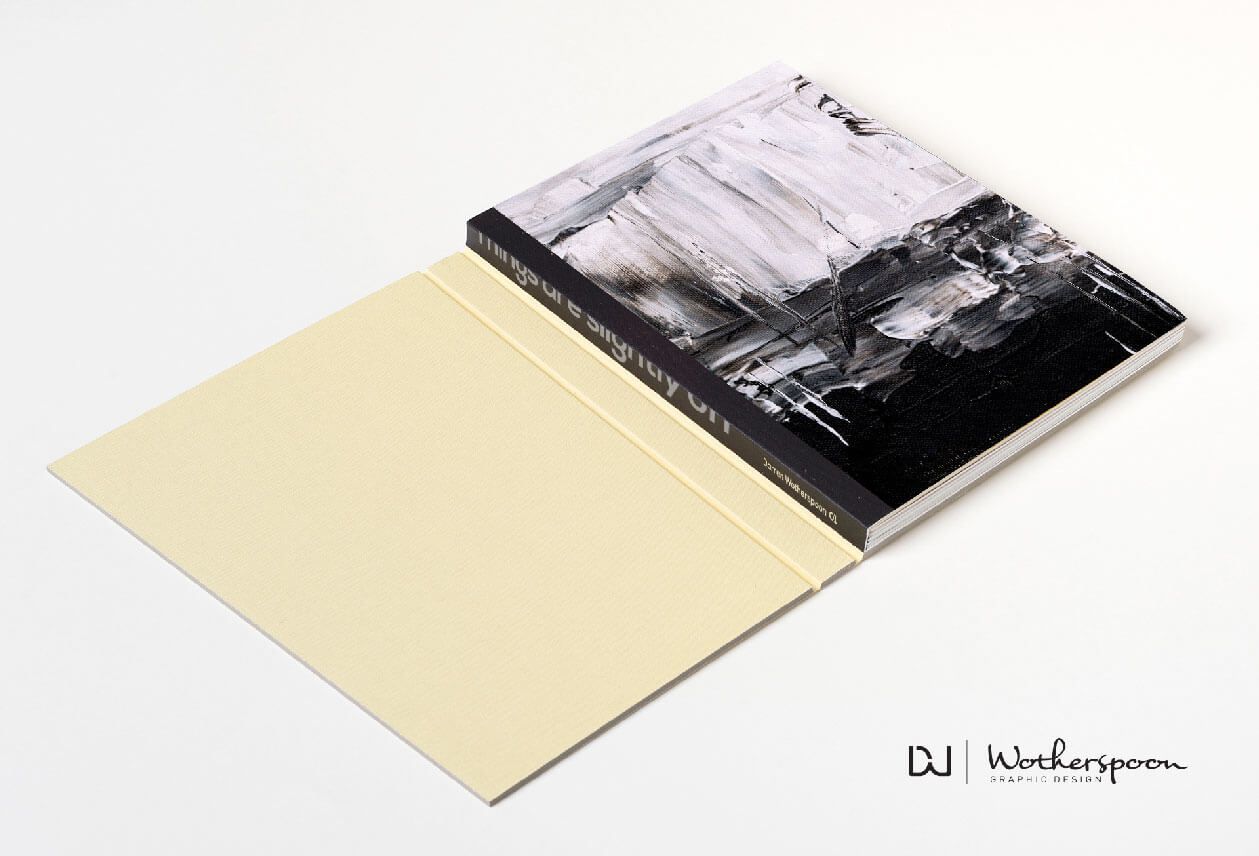 Book with a black and white abstract painting on the cover, open on a beige surface.