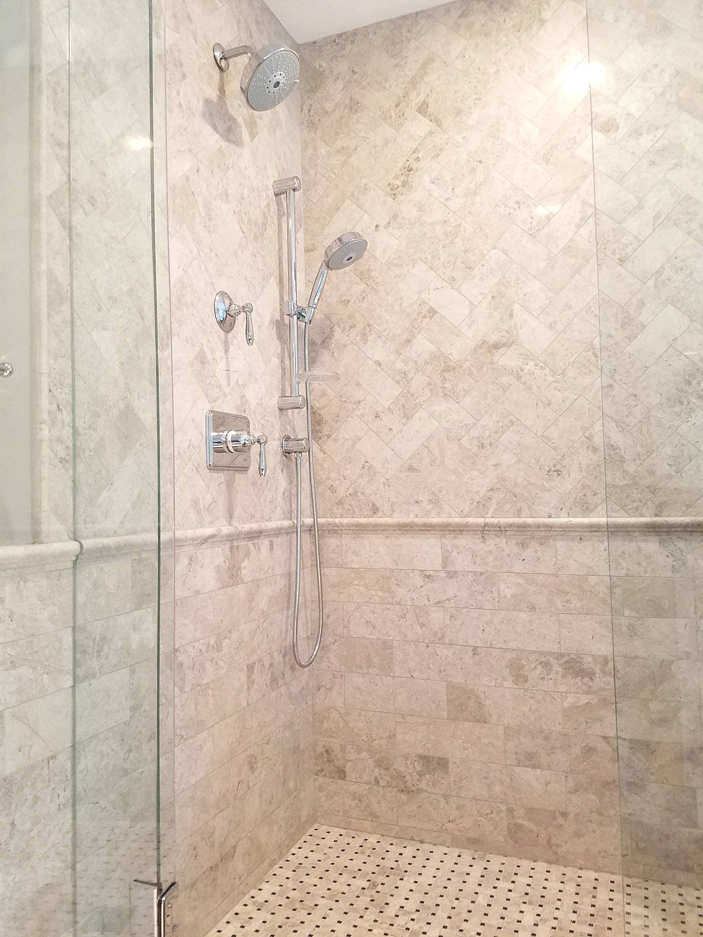A walk in shower with a glass door and a shower head