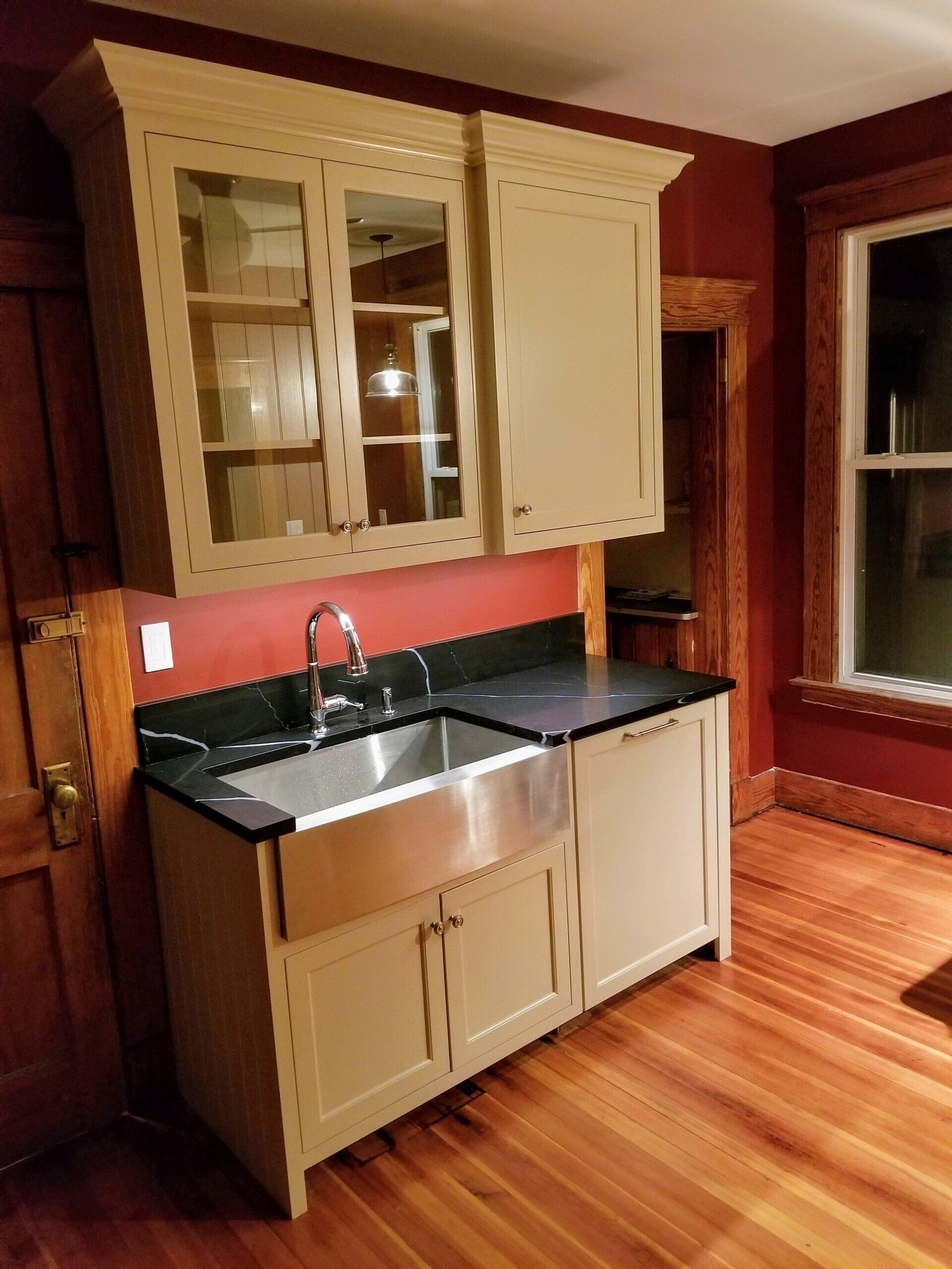 A kitchen with beige cabinets and a stainless steel sink
