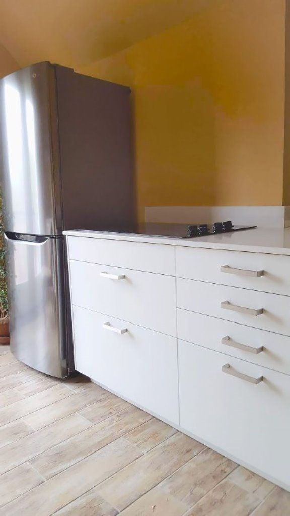A kitchen with a stainless steel refrigerator and white cabinets.