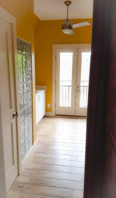 A hallway with yellow walls and a ceiling fan